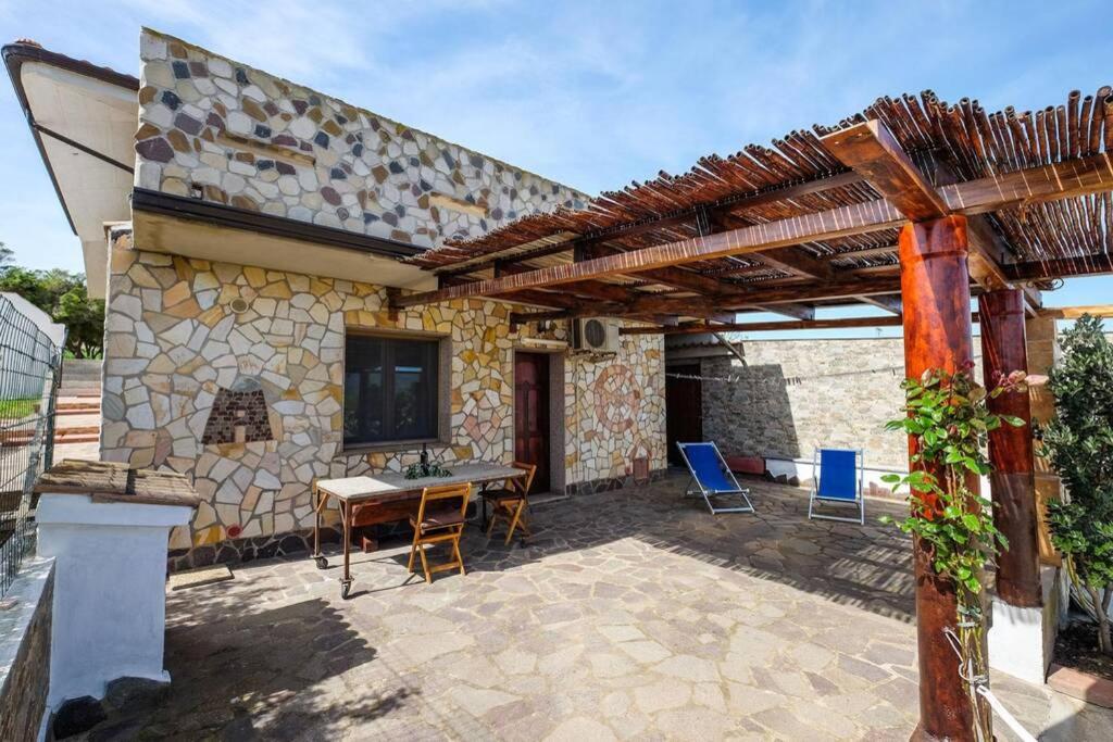 um pátio de uma casa com uma mesa e cadeiras em Apartment Nuraghe, barrierefrei, auf Olivenhain em Gonnesa