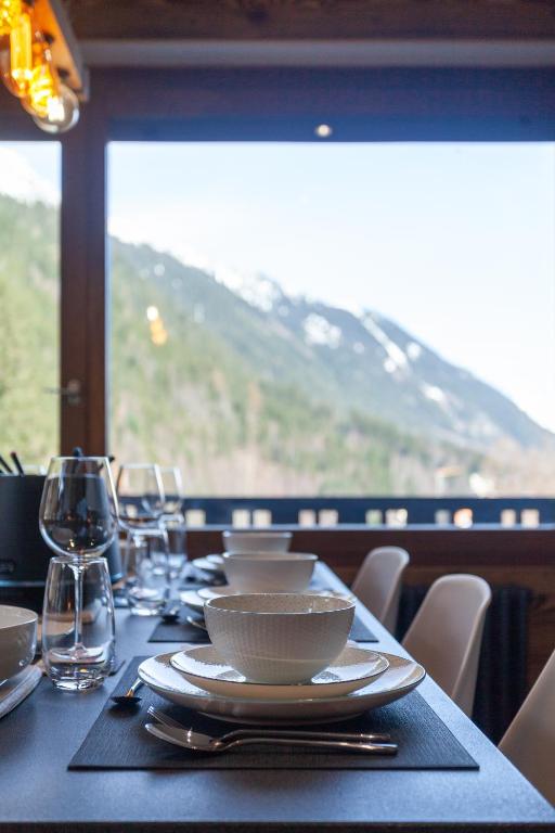 a table with plates and glasses on a table with a view at Apartment Brevent Fodera in Chamonix