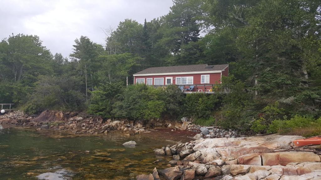 a red house on a hill next to a river at TeelCoveCottageMaine in Saint George