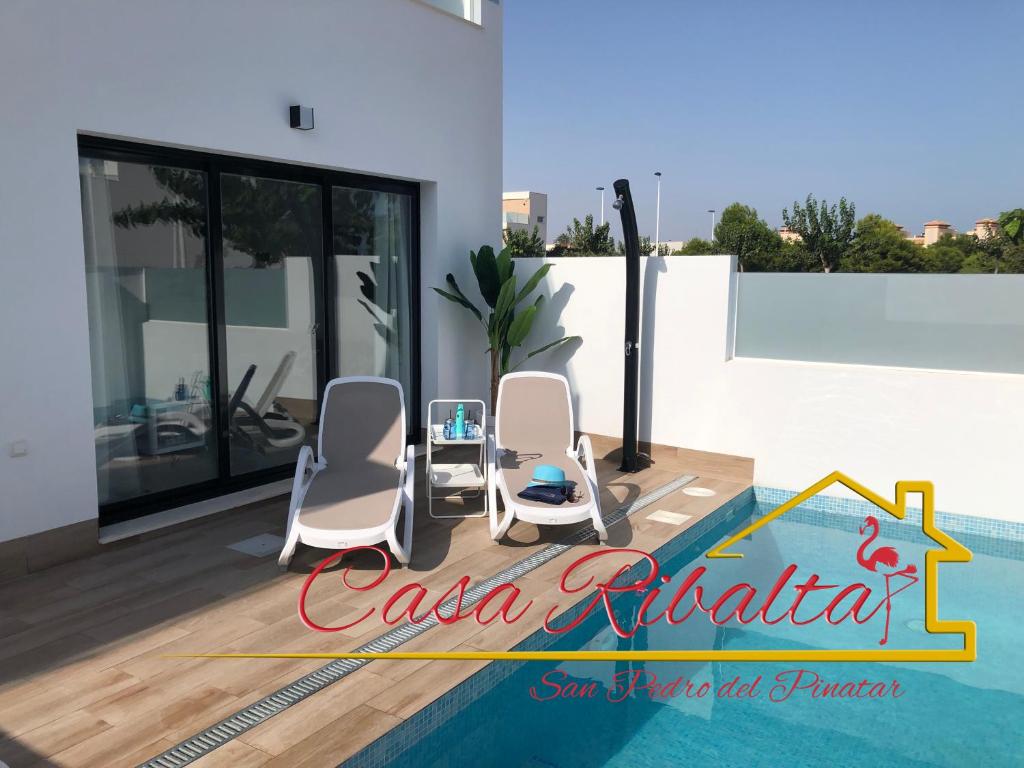 two chairs and a table next to a swimming pool at Casa Ribalta in San Pedro del Pinatar