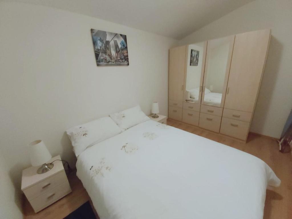 1 dormitorio con cama blanca y espejo en Mountain Village Apartment Pinewood ***, en Vyšné Ružbachy