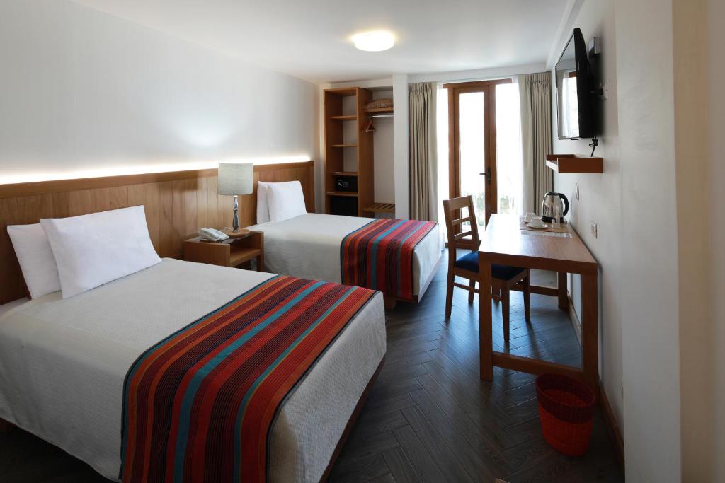 a hotel room with two beds and a desk at San Agustin Posada del Monasterio in Arequipa