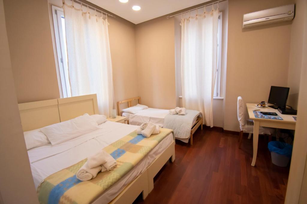 レッジョ・ディ・カラブリアにあるCasual Stay Cairoliのベッドが2つと机とコンピューターがある部屋