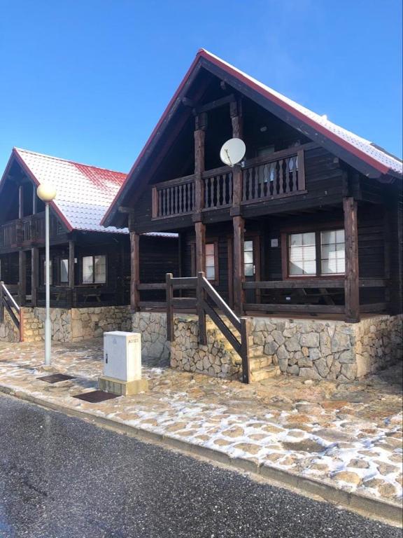 a large wooden building with a porch on a street at Chalé 6 in Penhas da Saúde