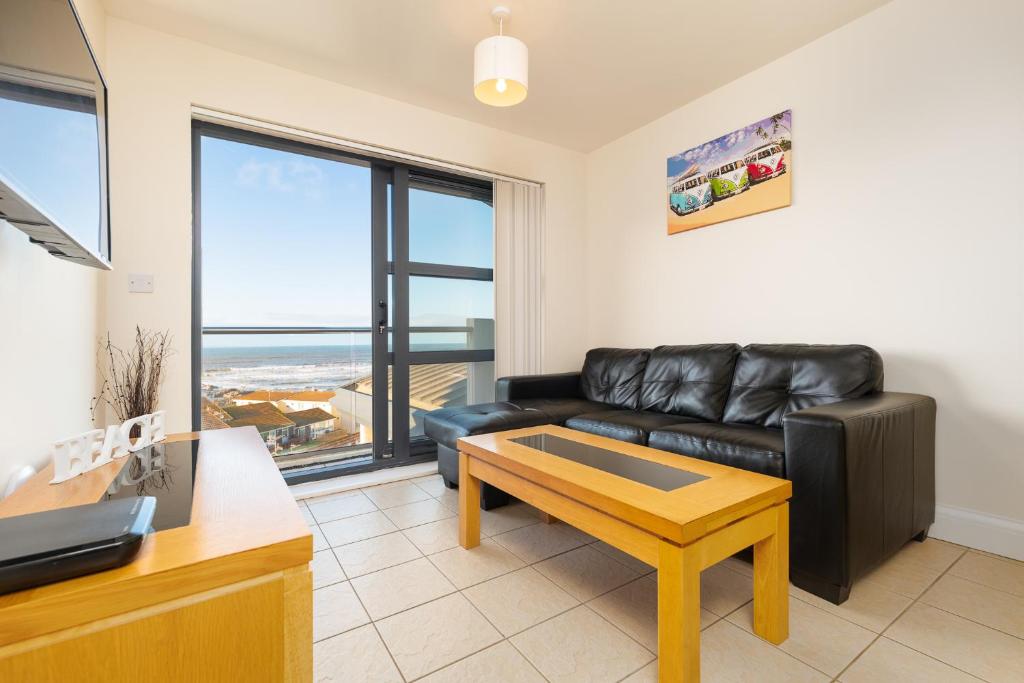 a living room with a leather couch and a table at West Beach - Holiday Apartments in Westward Ho