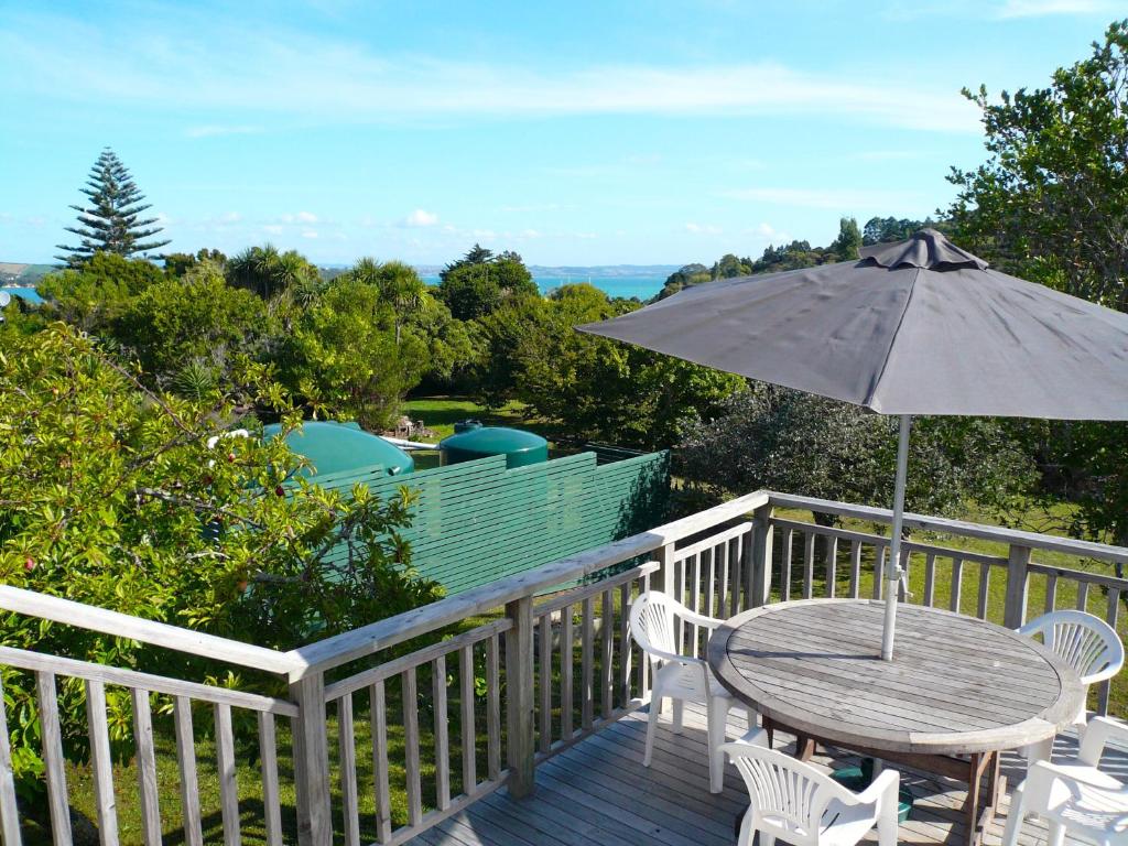 a wooden table and chairs with an umbrella on a deck at Ridge Cottage - Oneroa Holiday Home in Oneroa