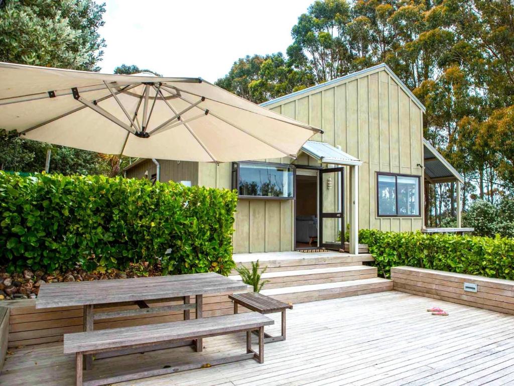 a wooden deck with benches and an umbrella at Two Rooms Onetangi - Onetangi Holiday Home in Onetangi