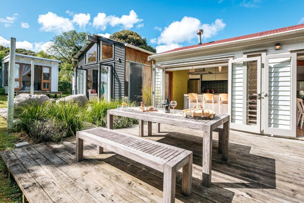 a wooden table and bench on a patio with a house at Kereru - Waiheke Holiday Home in Ostend