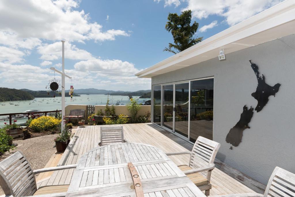a deck with chairs and a table with a view of the water at Captain's Quarters - Opua Holiday Home in Opua