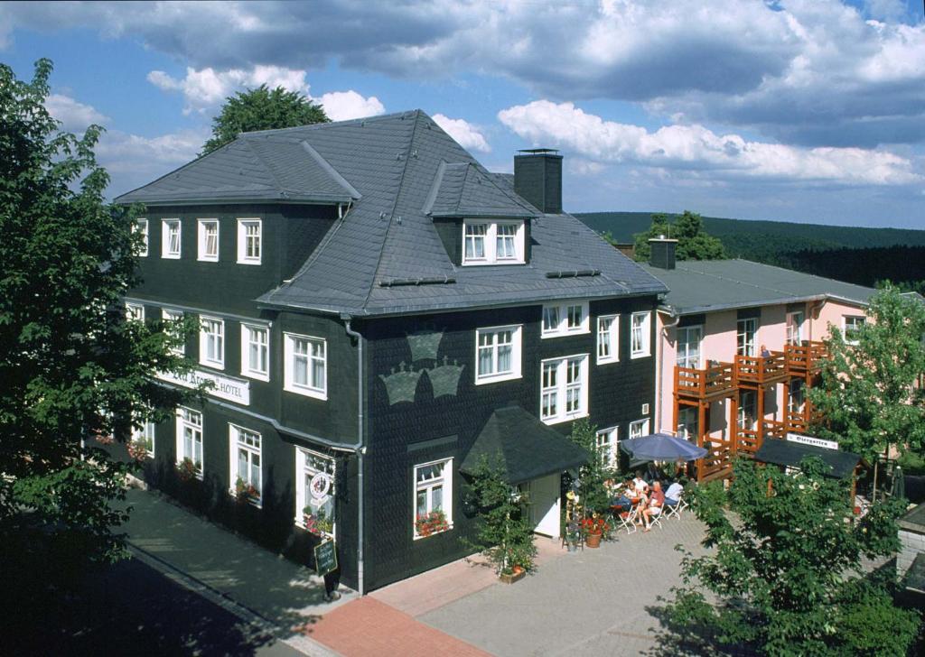 a large black house with people sitting outside of it at Hotel Drei Kronen in Frauenwald