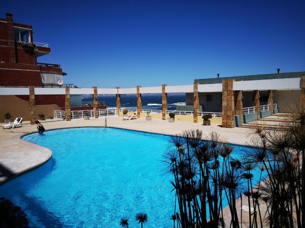 una gran piscina azul con el océano en el fondo en El Encanto de Reñaca viña del mar, Excelente vista al mar bajada directa a la playa, en Viña del Mar