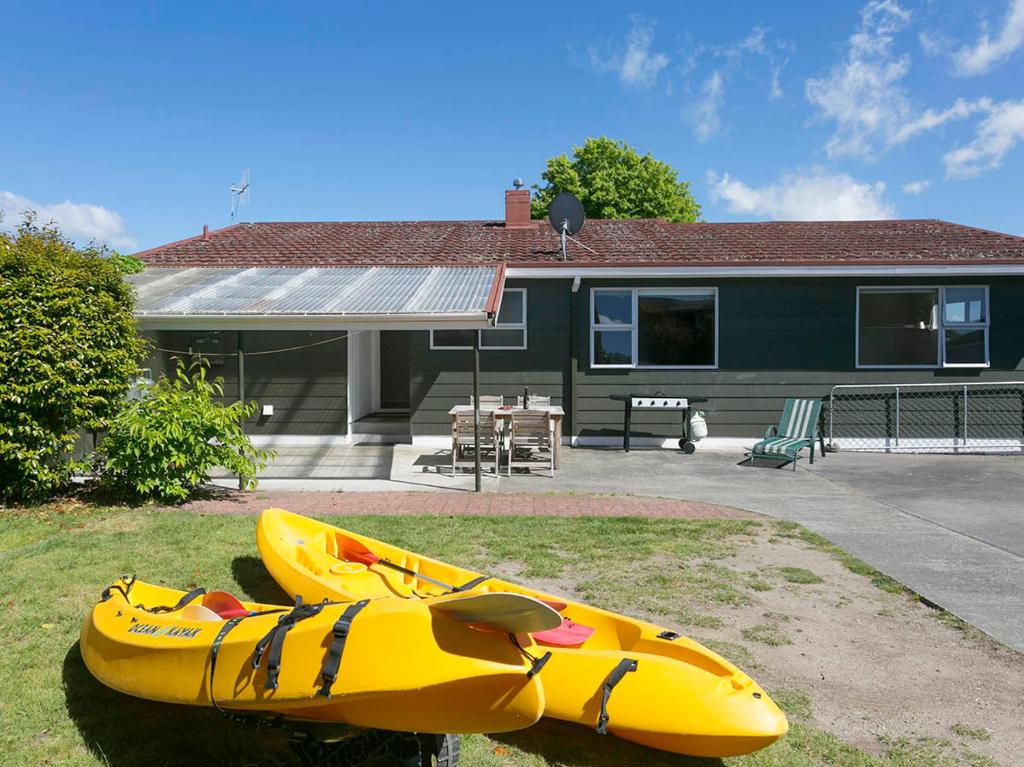 - un kayak jaune assis devant une maison dans l'établissement This Bach Has it All - Rainbow Point Holiday Home, à Taupo