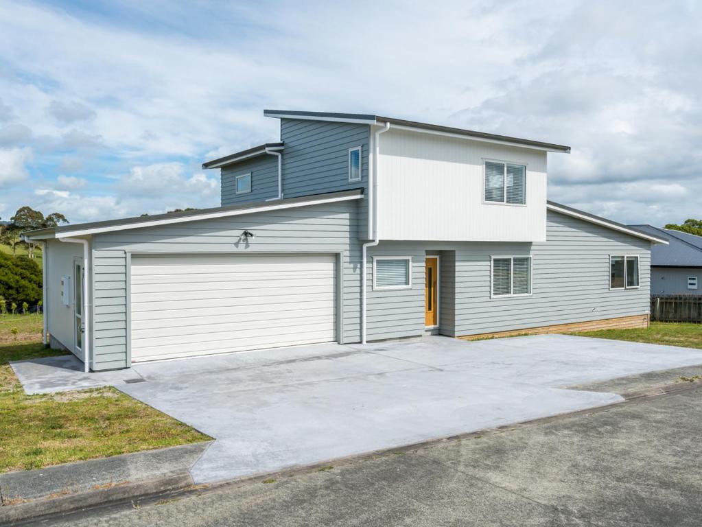 une grande maison blanche avec un garage dans l'établissement Ruakaka Sands - Ruakaka Holiday Home, à Ruakaka