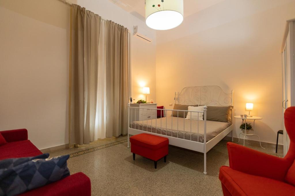 a small bedroom with a bed and a red chair at Sichelgaita Apartment in Salerno