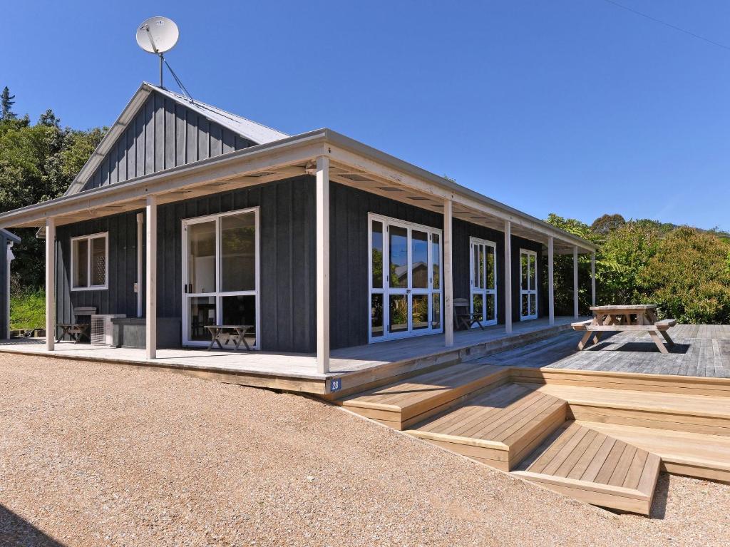 a black house with a picnic table on a deck at Tuis on Tata - Golden Bay Home Tata Beach in Tarakohe