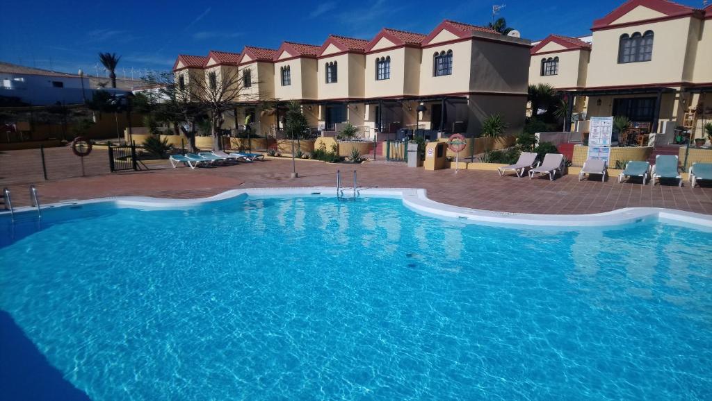 une grande piscine bleue en face d'un bâtiment dans l'établissement Green Oasis by the pool, à Costa Calma