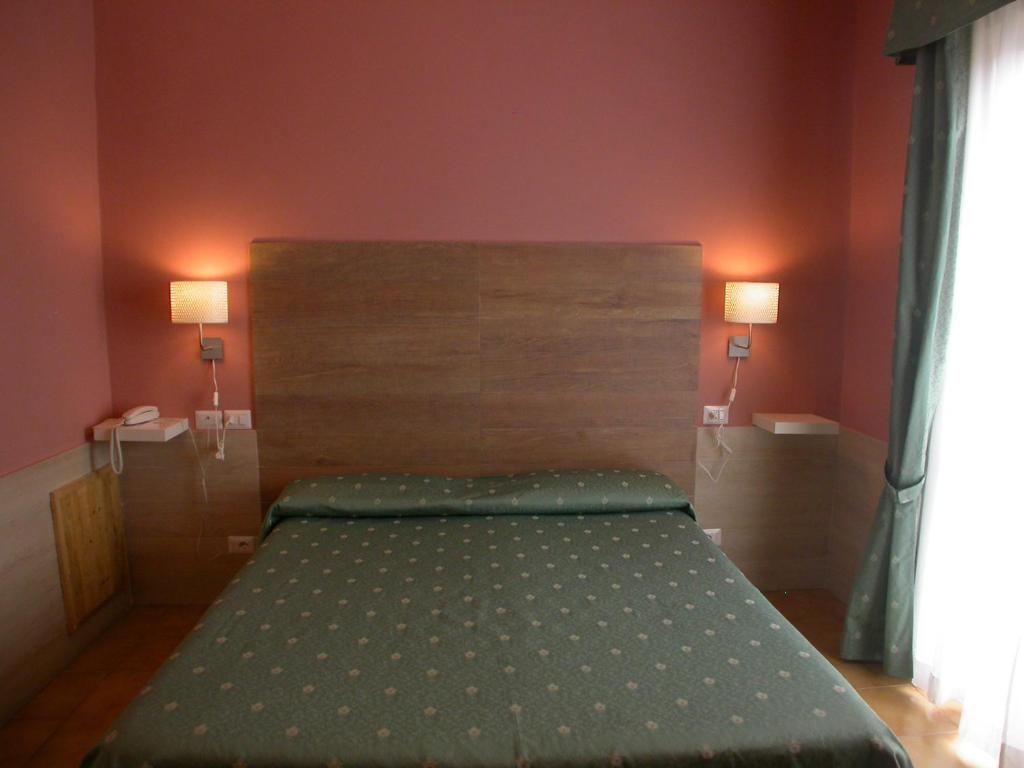 a bed in a bedroom with two lamps on the wall at Hotel Il Roscio in Attigliano