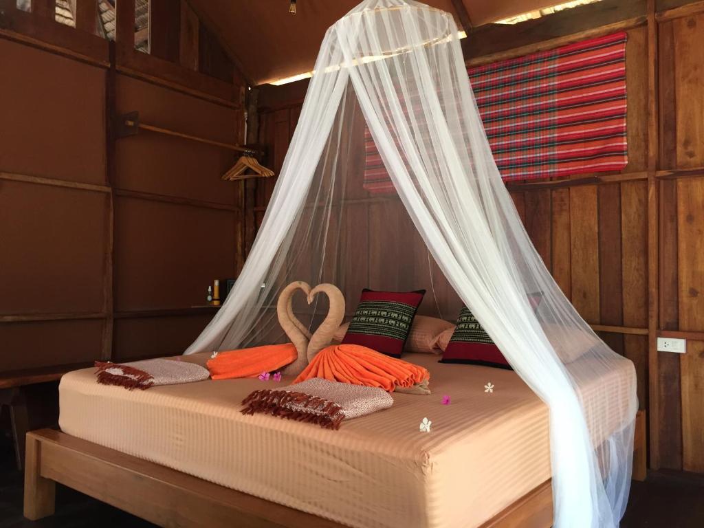 a bed in a room with a mosquito net at Sea Rounding in Ko Phra Thong