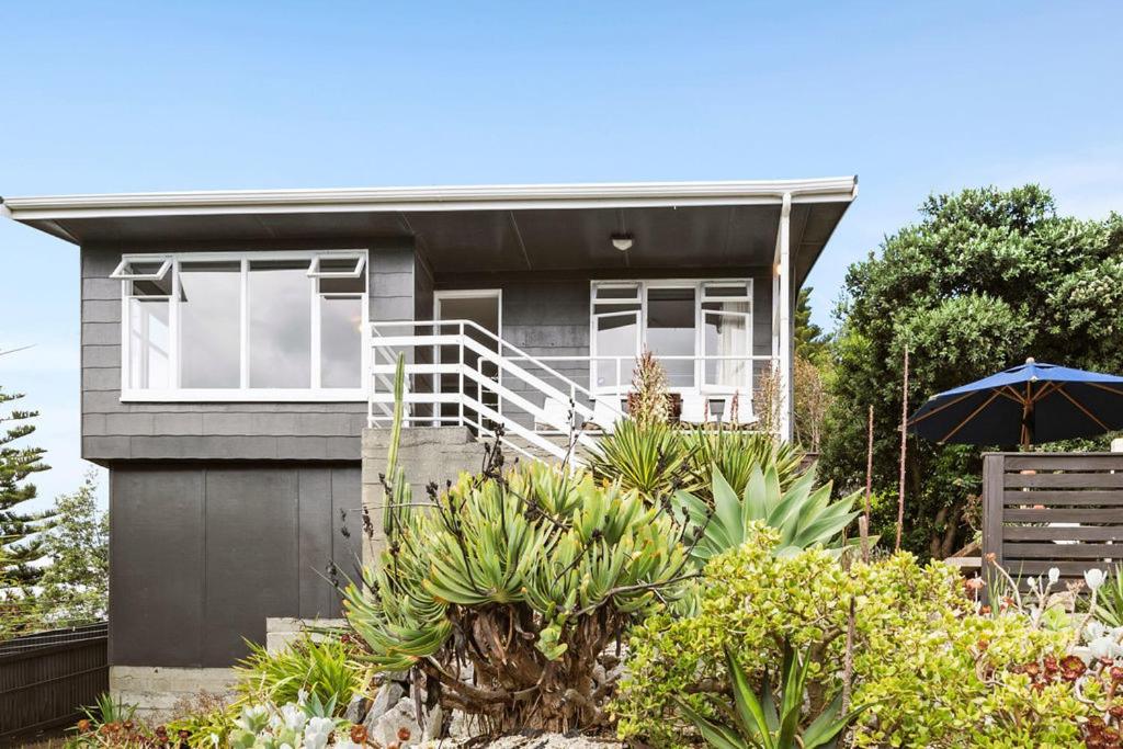 a house with an umbrella in front of it at Seaside House - Waikanae Beach Bach in Waikanae