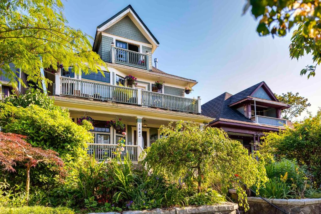 a large yellow house with balconies and trees at The Ivy on Parker Guest House in Vancouver