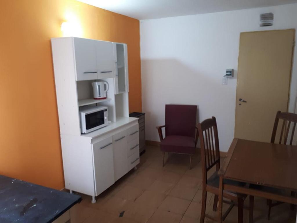 eine Küche mit einem weißen Schrank mit einer Mikrowelle und einem Tisch in der Unterkunft Habitacion economica con estacionamiento Necochea in Necochea
