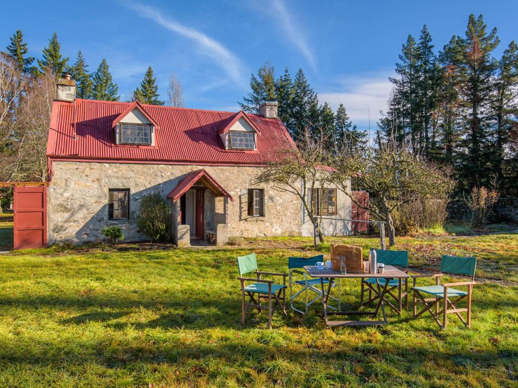 a house with a table and chairs in front of it at Wanaka Stone Cottage - Wanaka Holiday Home in Wanaka