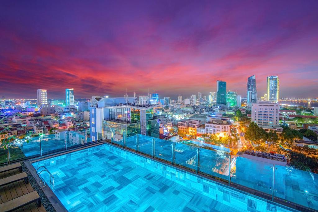 a city skyline at night with a swimming pool at Seahorse Tropical Da Nang Hotel by Haviland in Da Nang
