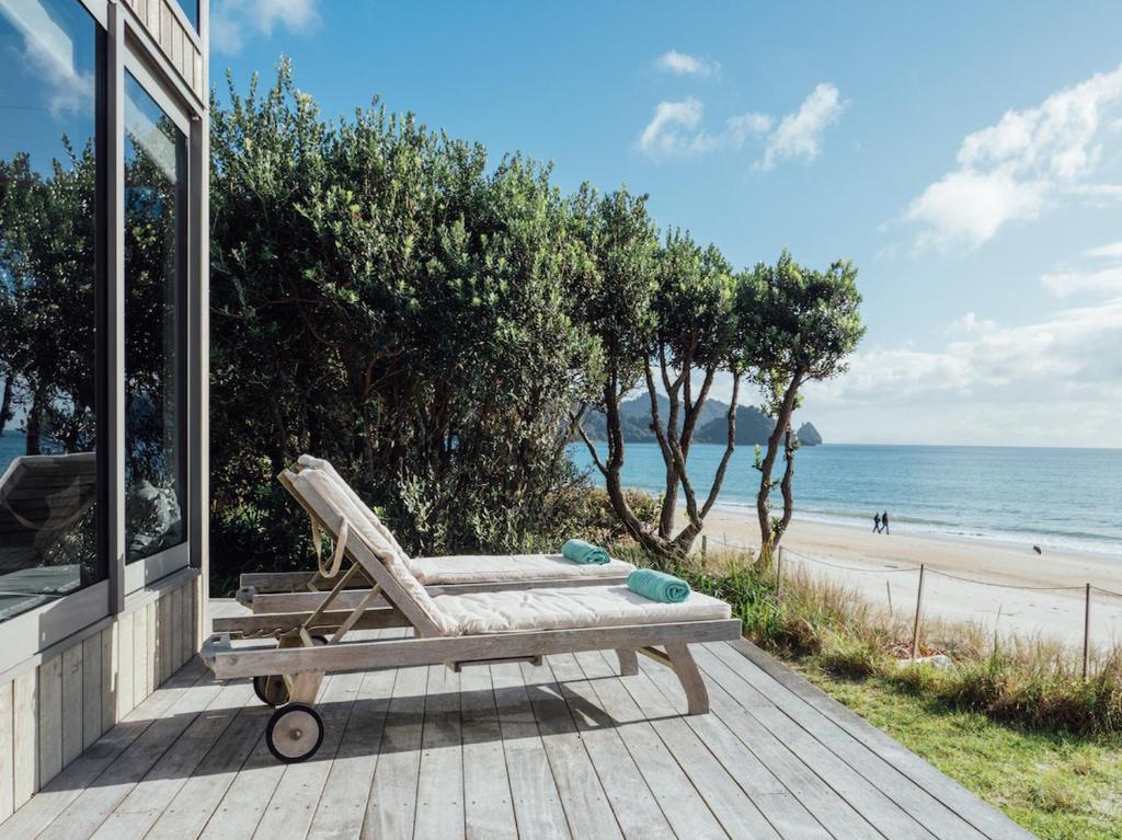 eine Bank auf einer Veranda mit Blick auf den Strand in der Unterkunft The Breakers - Whangapoua Executive Holiday Home in Whangapoua