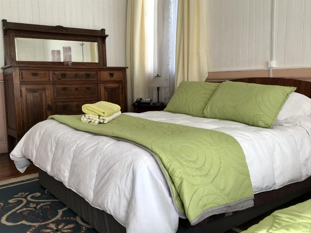 a bed with a green comforter and a mirror at Hospedaje Mery in Cañete