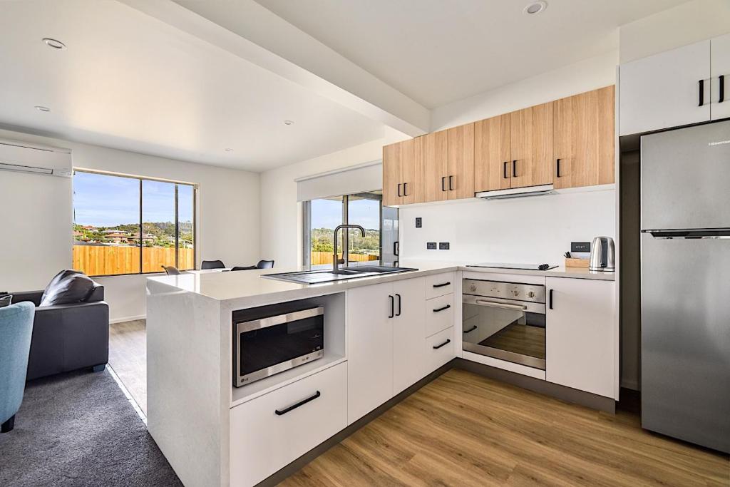 a kitchen with white cabinets and a large window at Southern Apartments Launceston in Launceston