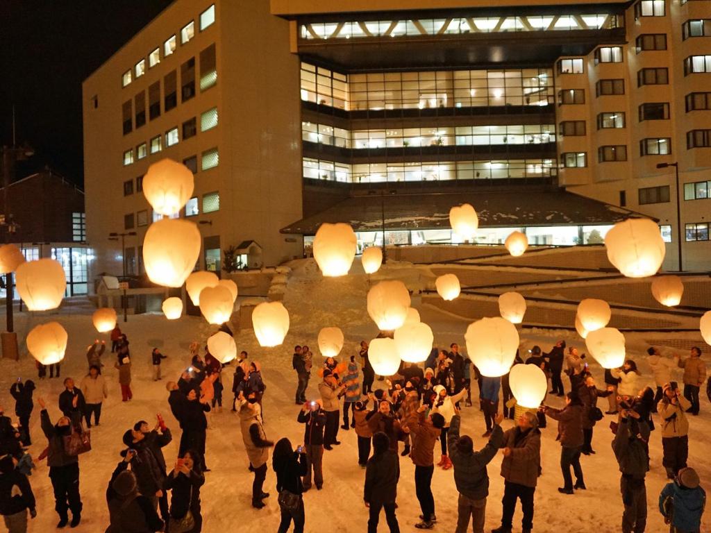 un gruppo di persone con lanterne di carta di fronte a un edificio di New Greenpia Tsunan a Tsunan