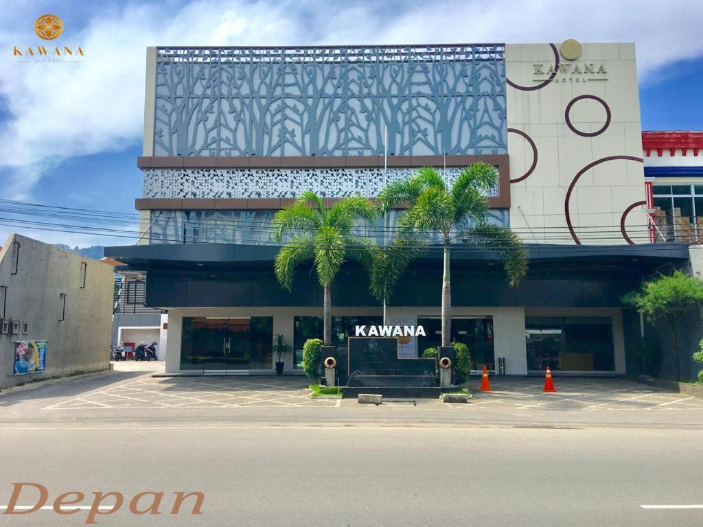 een gebouw met palmbomen ervoor bij KAWANA HOTEL in Kampungdurian