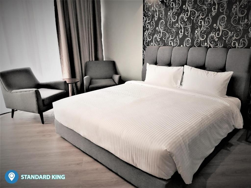 a bedroom with a large bed and two chairs at Desa Selatan Resort Pengerang in Pengerang