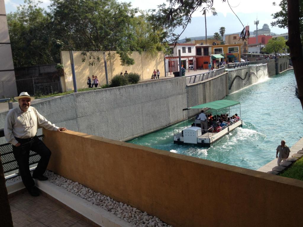 a man leaning against a wall next to a boat in a river at Departamento en Paseo Santa Lucía con Terraza D2 in Monterrey