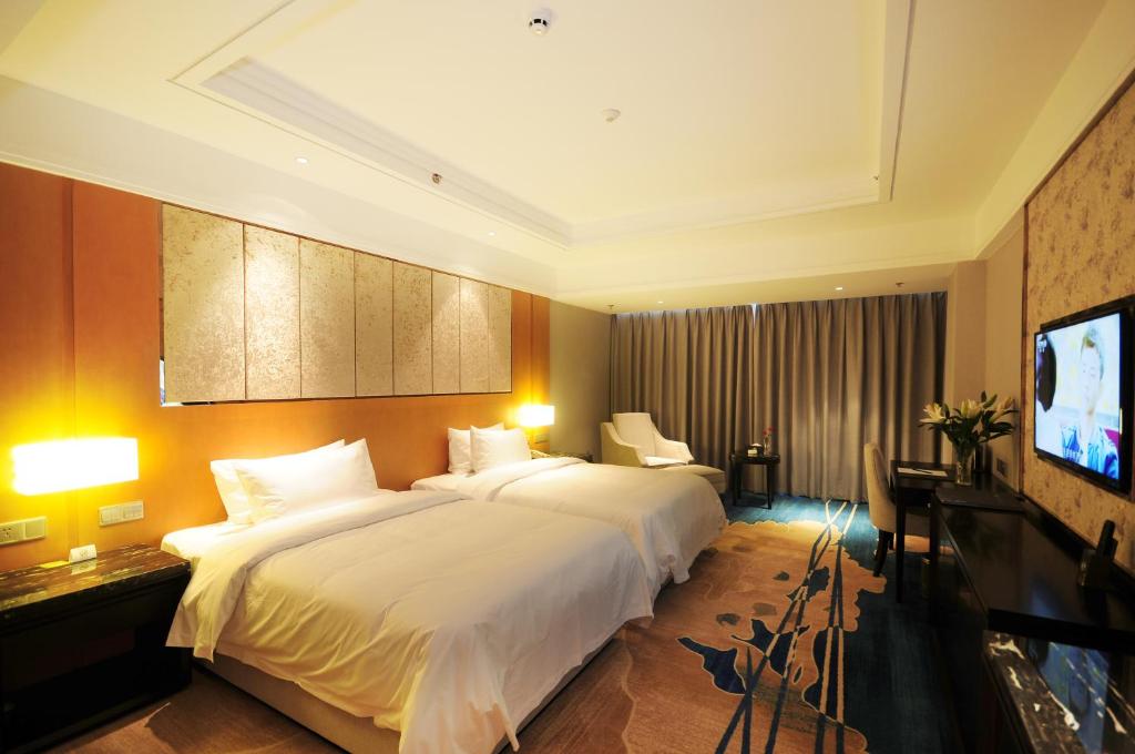 um quarto de hotel com uma cama grande e uma televisão de ecrã plano em Airport Jianguo Hotel em Chengdu