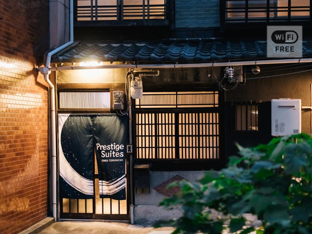 uma entrada para um edifício com uma placa na porta em Prestige Suites Osaka Teradacho em Osaka