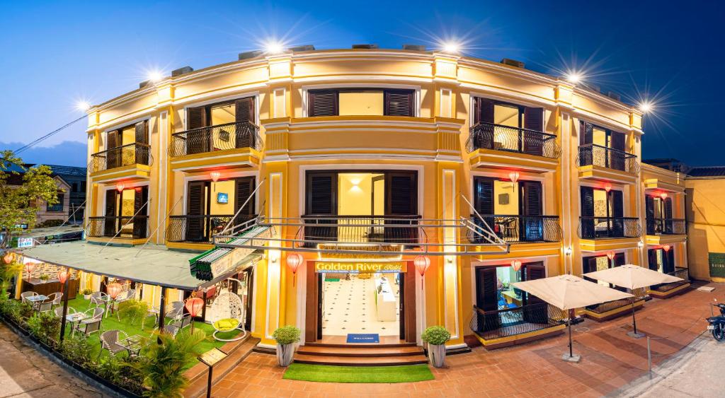 a large yellow building with lights on it at Golden River Hotel in Hoi An
