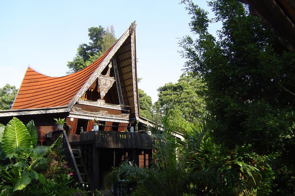 a house with an orange roof and some trees at Liberta Homestay in Tuktuk Siadong