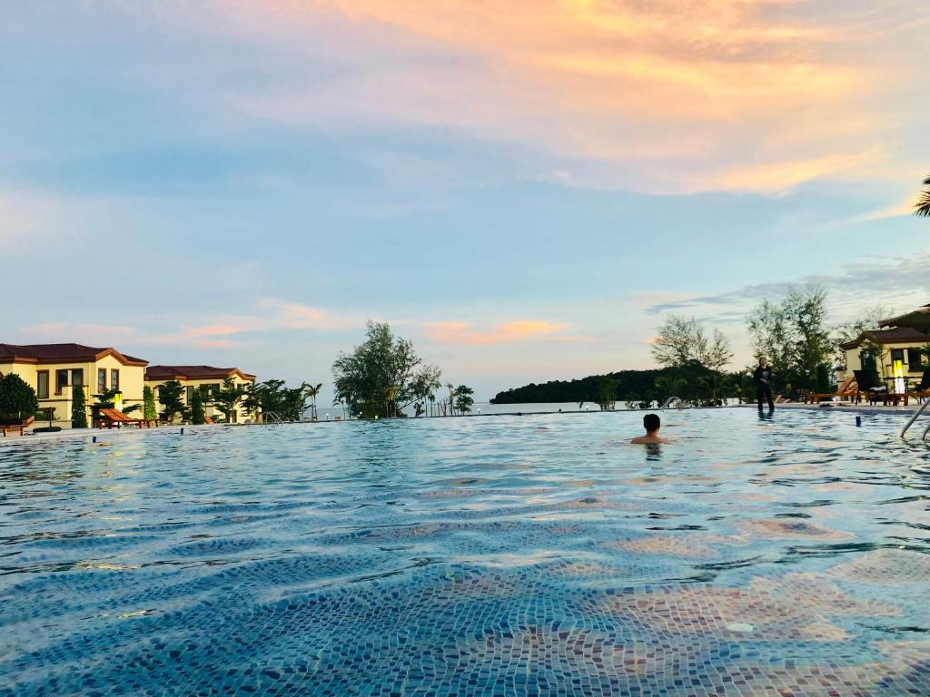 uma pessoa na água numa piscina de resort em Sealong Bay ZhongQi Conifer Hotel 海龙湾中启康年酒店 em Sihanoukville