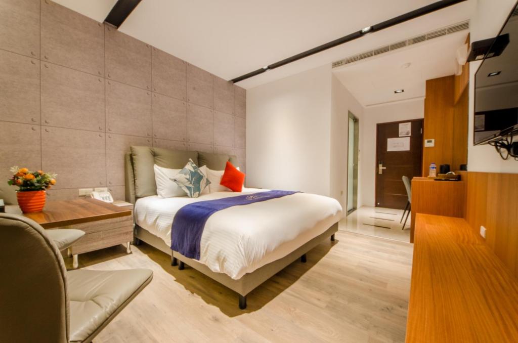 a bedroom with a bed and a desk and a room at Mucun Hot Spring Resort in Jiaoxi