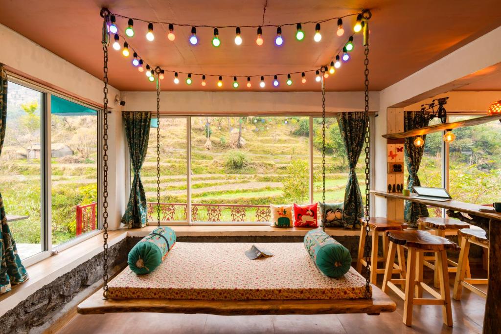 a room with a large window with a swing and lights at Zostel Plus Mussoorie- Kempty in Mussoorie