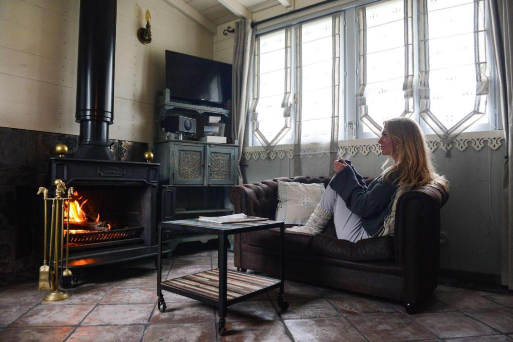 a woman sitting on a couch in a room with a fireplace at Domaine de l’Escuderia in Parentis-en-Born