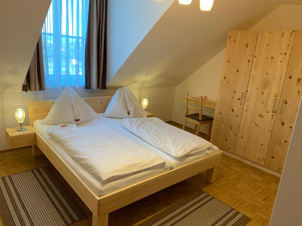 una camera da letto con un grande letto con lenzuola bianche di Feldkirchnerhof a Feldkirchen bei Graz