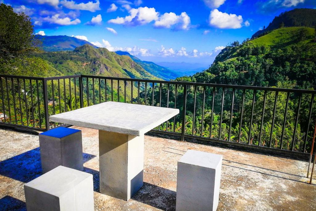 a white bench sitting on top of a balcony with mountains at Paraiso Guest House in Ella