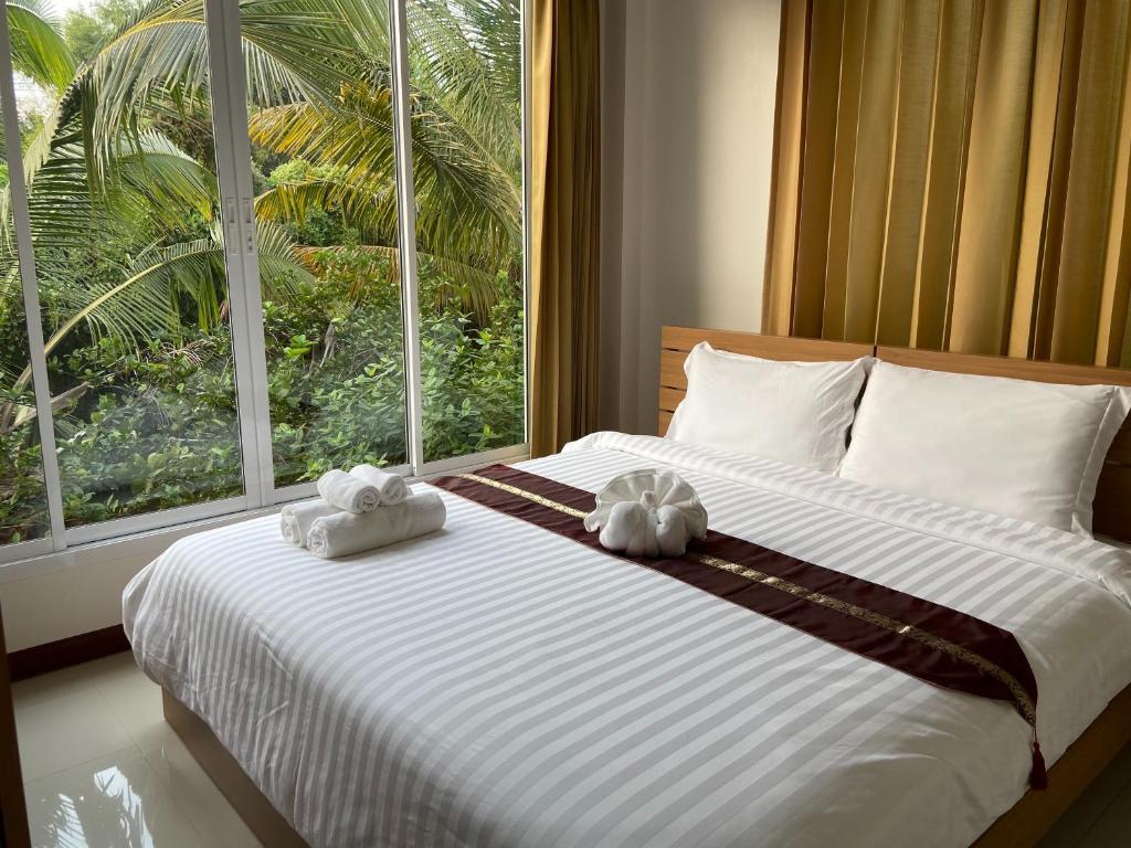 1 dormitorio con 1 cama grande y toallas. en ร่มปาล์มรีสอร์ท สระบุรี Rompalm Saraburi, en Saraburi