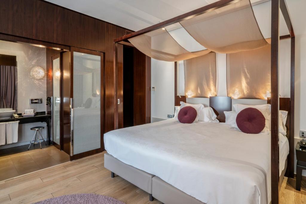 a bedroom with a large white bed and a bathroom at Vincci Palace in Valencia