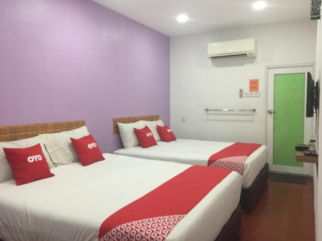 two beds in a room with red and white pillows at OYO 89671 Changlun Star Motel in Changlun