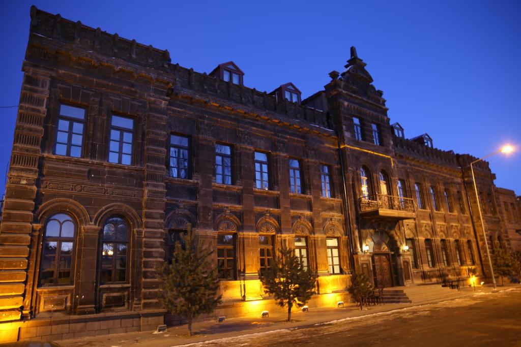 een groot bakstenen gebouw 's nachts bij Cheltikov Hotel in Kars