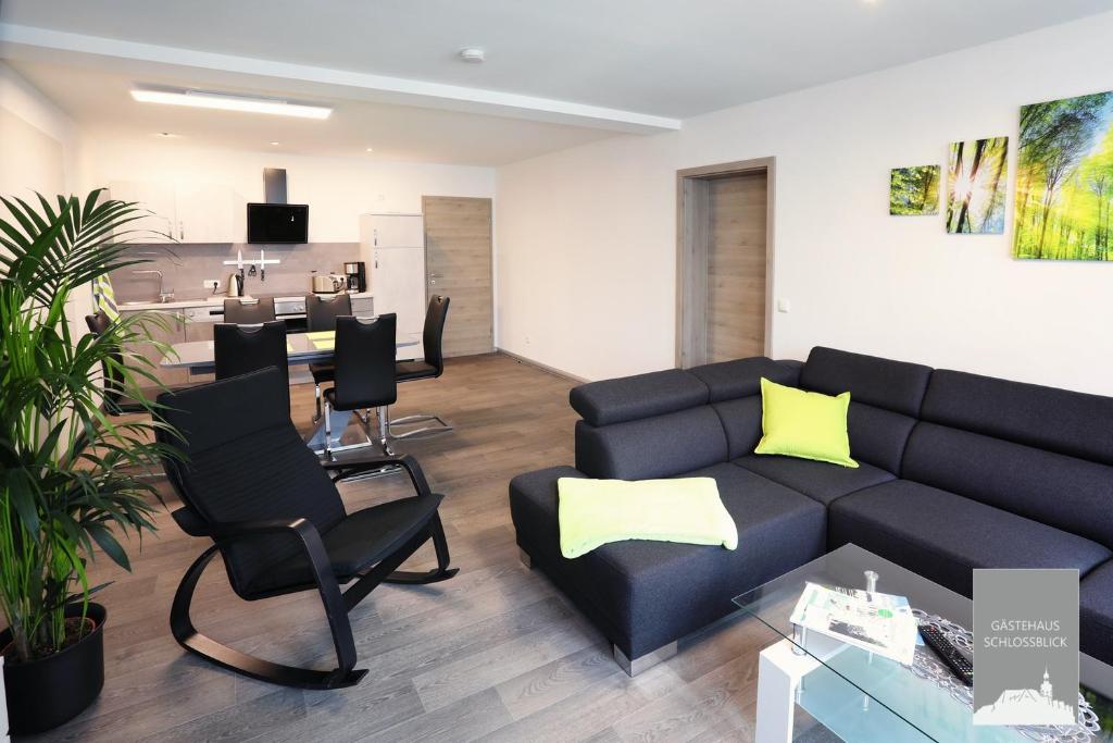 uma sala de estar com um sofá preto e almofadas amarelas em Gästehaus Schlossblick Greiz em Greiz
