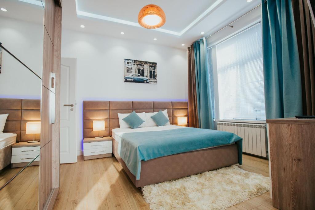 a bedroom with a bed with blue sheets and a window at Color Apartments Corneliu Coposu 1A street in Bucharest